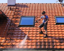Worker is cleaning the roof and rainwater gutter with high pressure.
